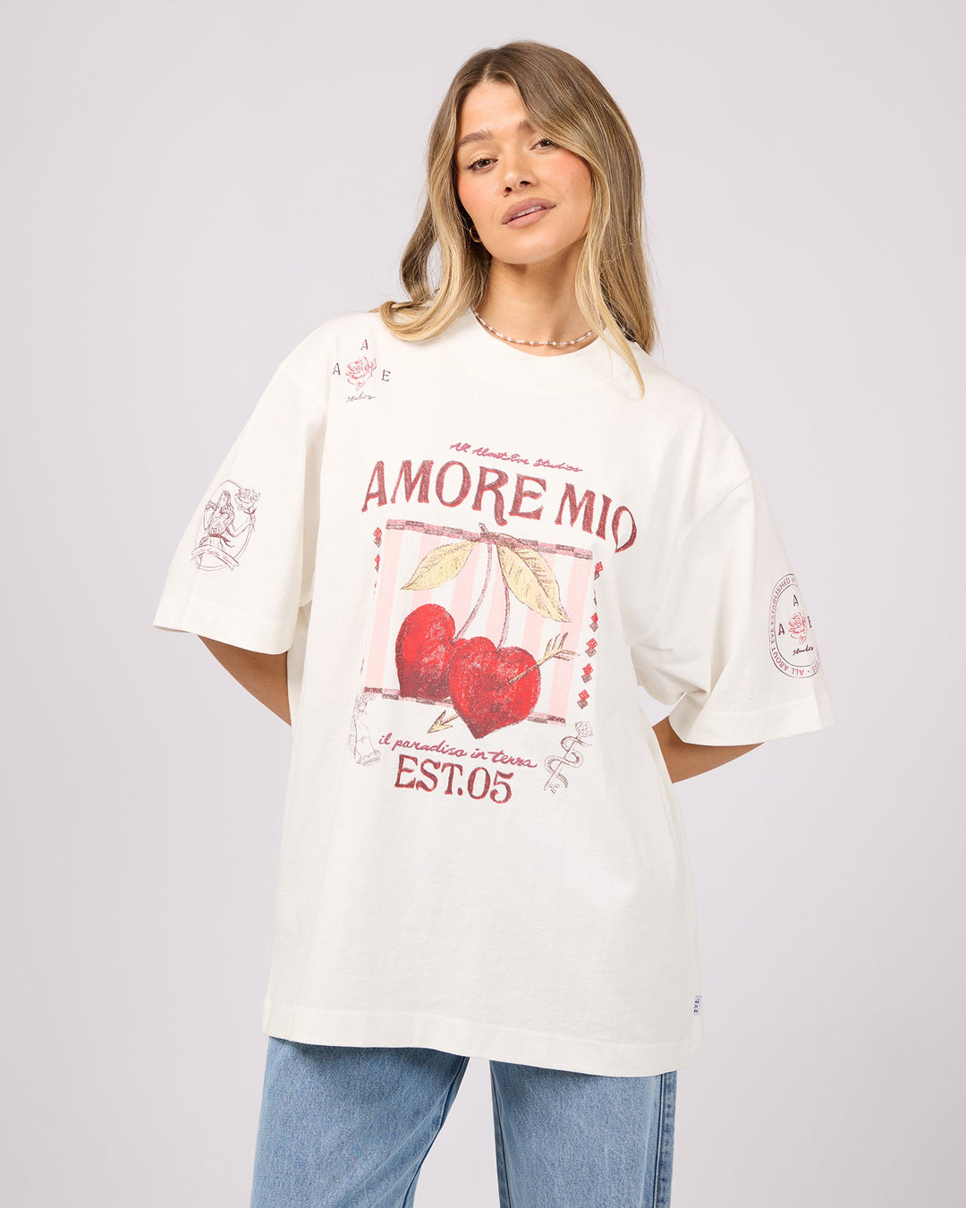 Woman wearing a white oversized t-shirt with red graphics and text on a plain background