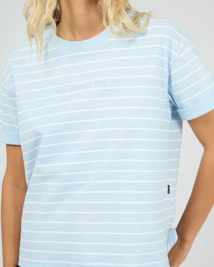 A close-up of a model wearing a light blue and white horizontally striped t-shirt with &
