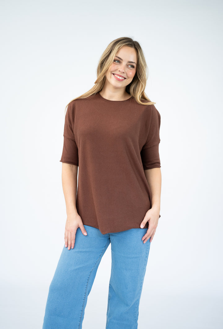 Woman wearing a brown top and blue jeans on a white background