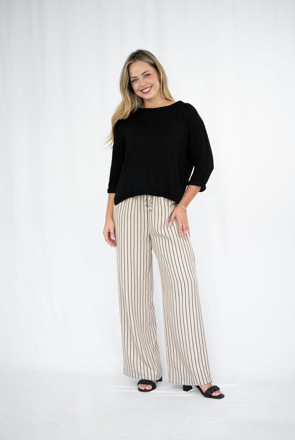 Woman wearing a black top and striped pants on a white background