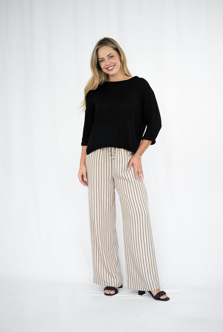 Woman wearing a black top and striped pants on a white background