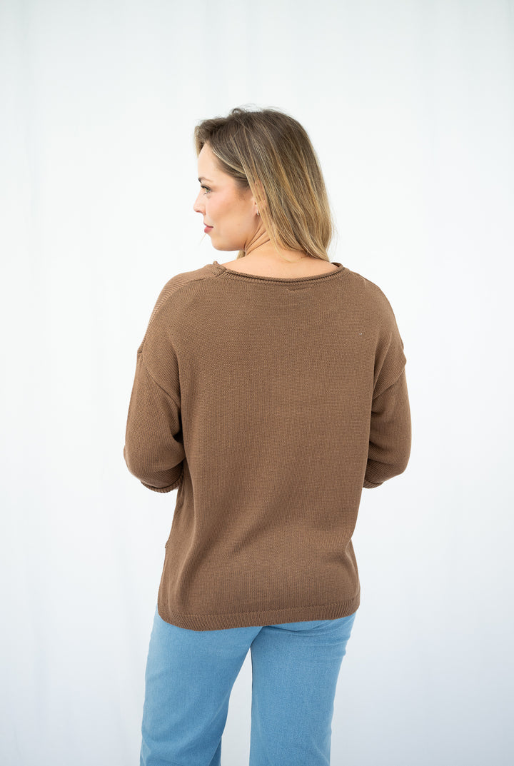 Woman wearing a brown sweater and light blue jeans on a white background