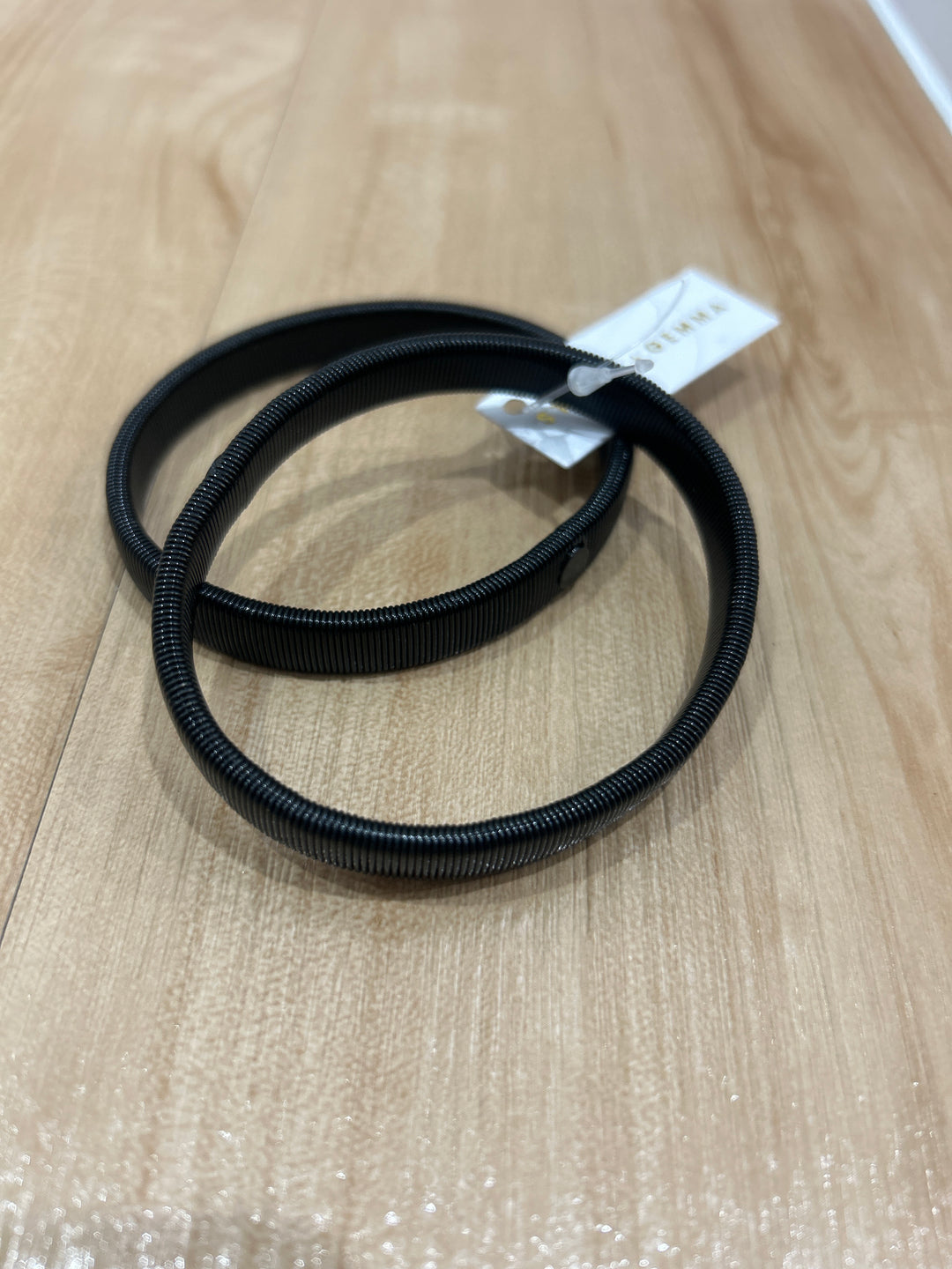 A pair of black elastic sleeve keepers displayed on a wooden surface.