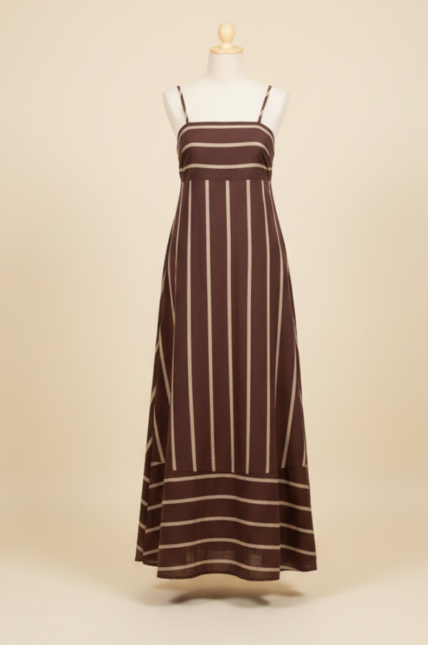 A sleeveless maxi dress on a mannequin, featuring vertical cream-colored stripes on a dusty mauve-brown fabric, set in a clothing store with racks of other garments in the background.