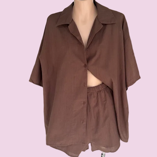 A brown short-sleeve button-up shirt with matching shorts displayed on a mannequin torso against a solid light pink background.