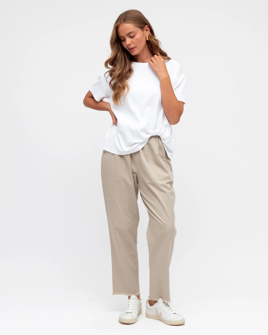 Woman wearing a white t-shirt and beige pants on a white background