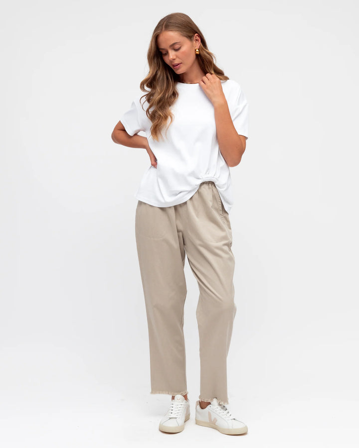 Woman wearing a white t-shirt and beige pants on a white background
