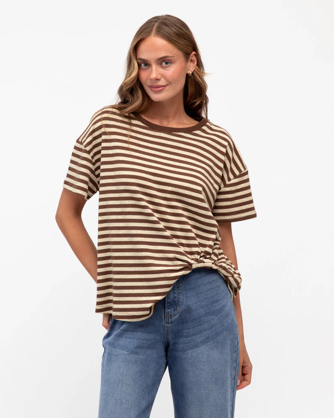 Woman wearing a brown and beige striped shirt with blue jeans on a white background
