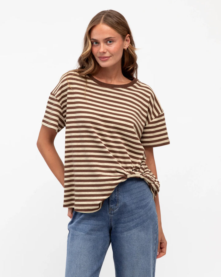 Woman wearing a brown and beige striped shirt with blue jeans on a white background