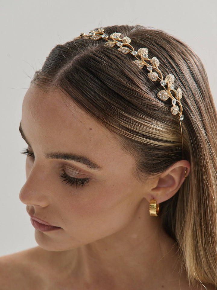 Woman wearing a decorative gold headband with a neutral background