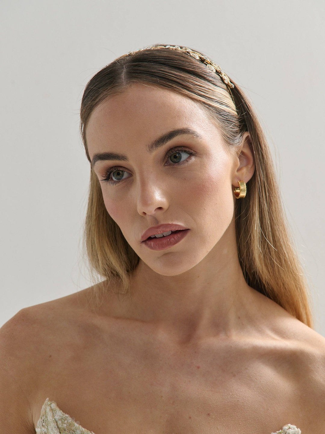 Woman with a headband and earrings against a plain background