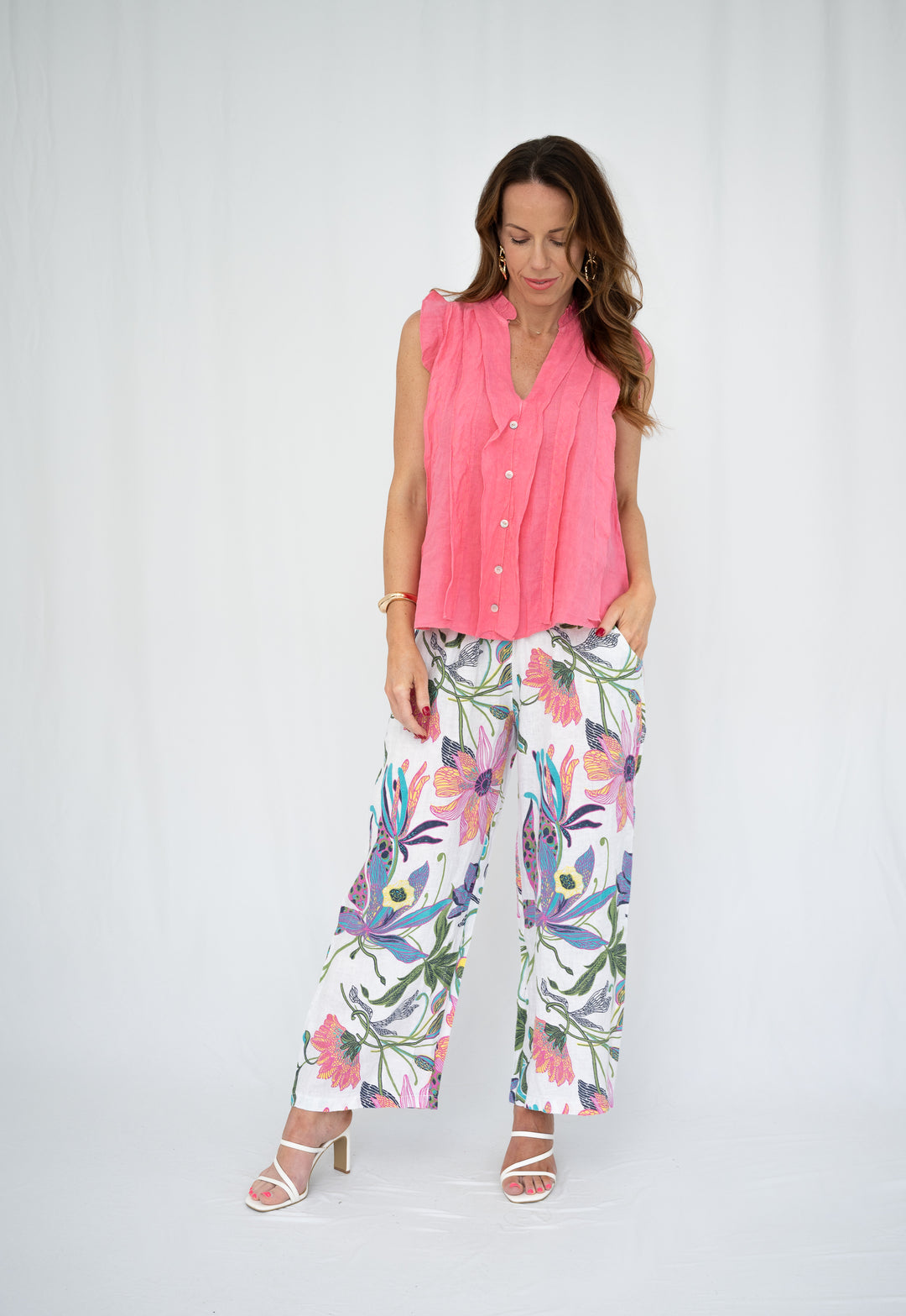 Woman wearing a pink blouse and floral pants on a white background