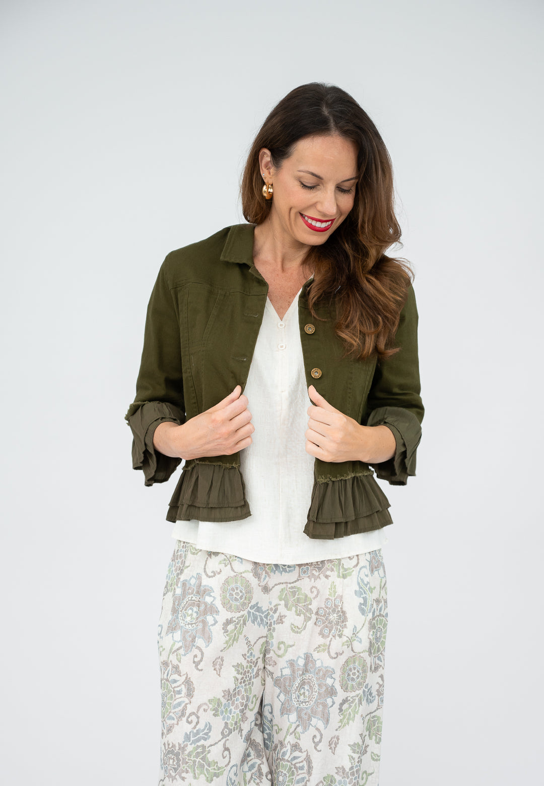 Woman wearing a green jacket with ruffled details on a white background