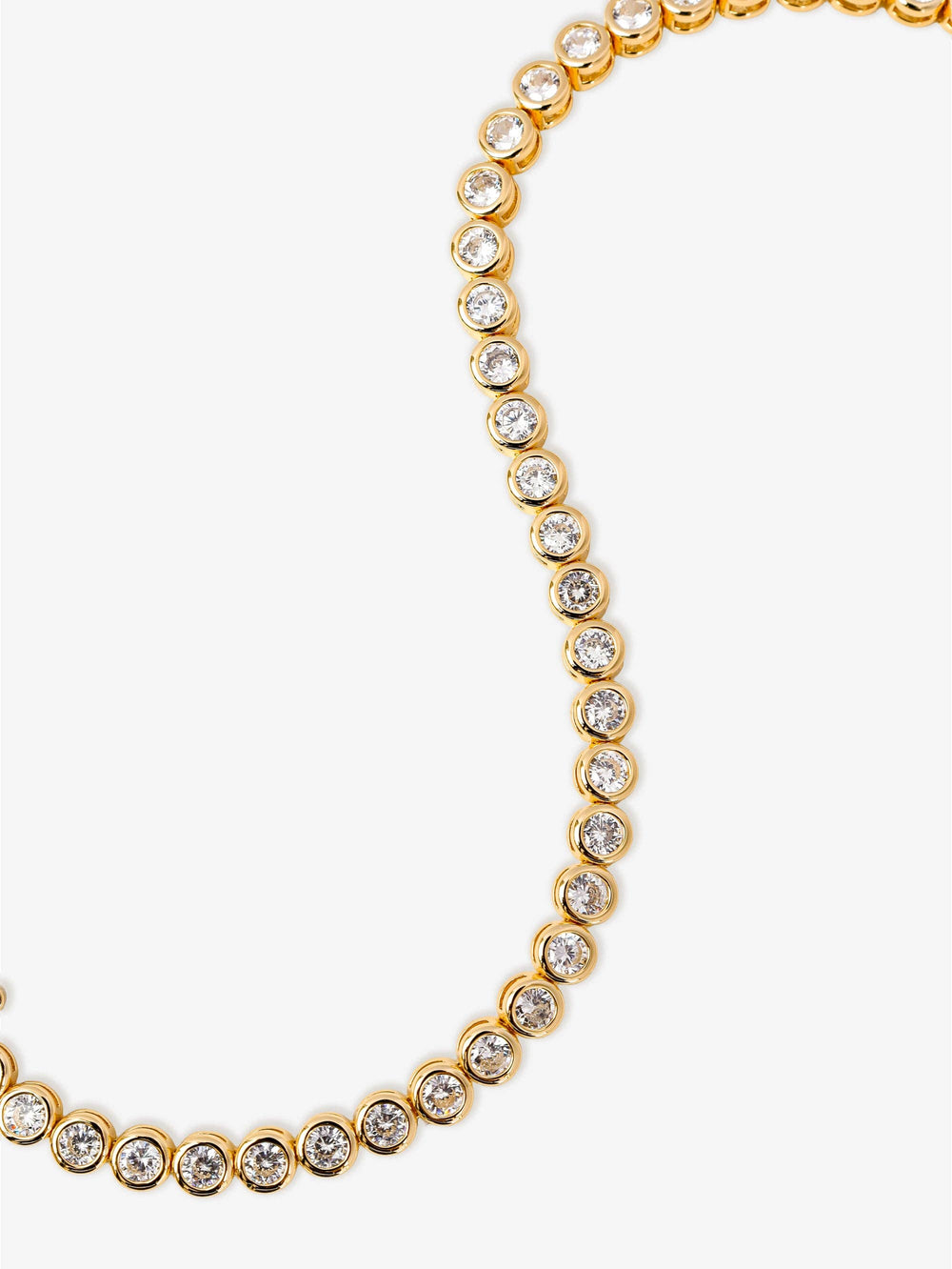 Gold necklace with clear stones on a white background