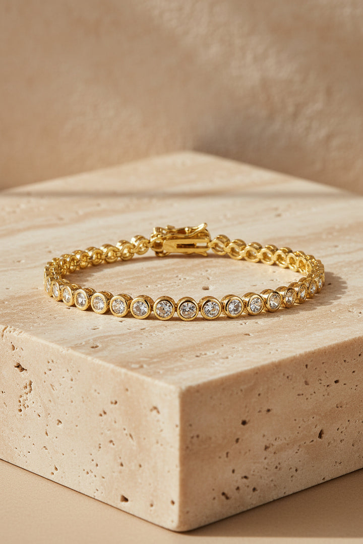 Gold bracelet with clear stones on a white background