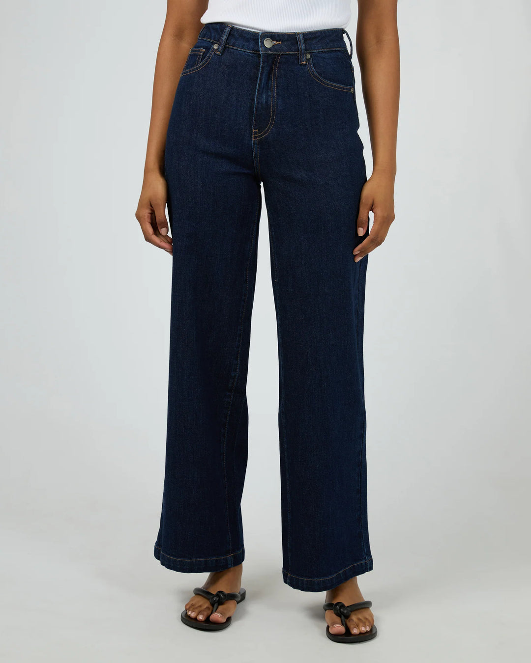 Person wearing dark blue jeans on a white background