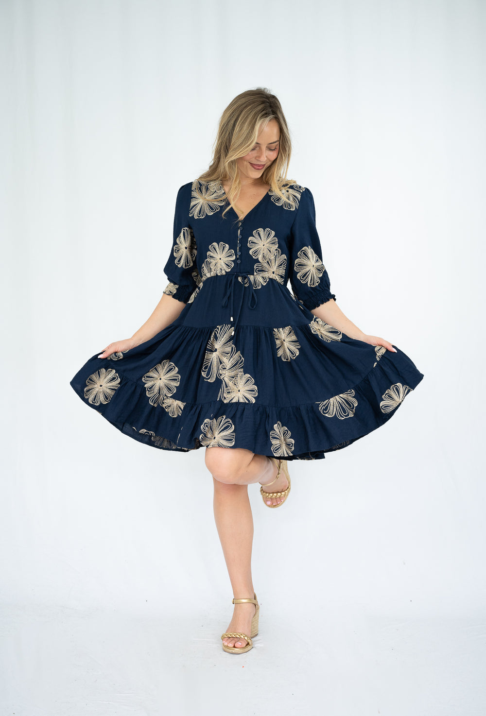 Woman wearing a navy dress with floral patterns on a white background