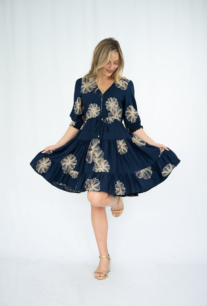 Woman wearing a navy dress with floral patterns on a white background