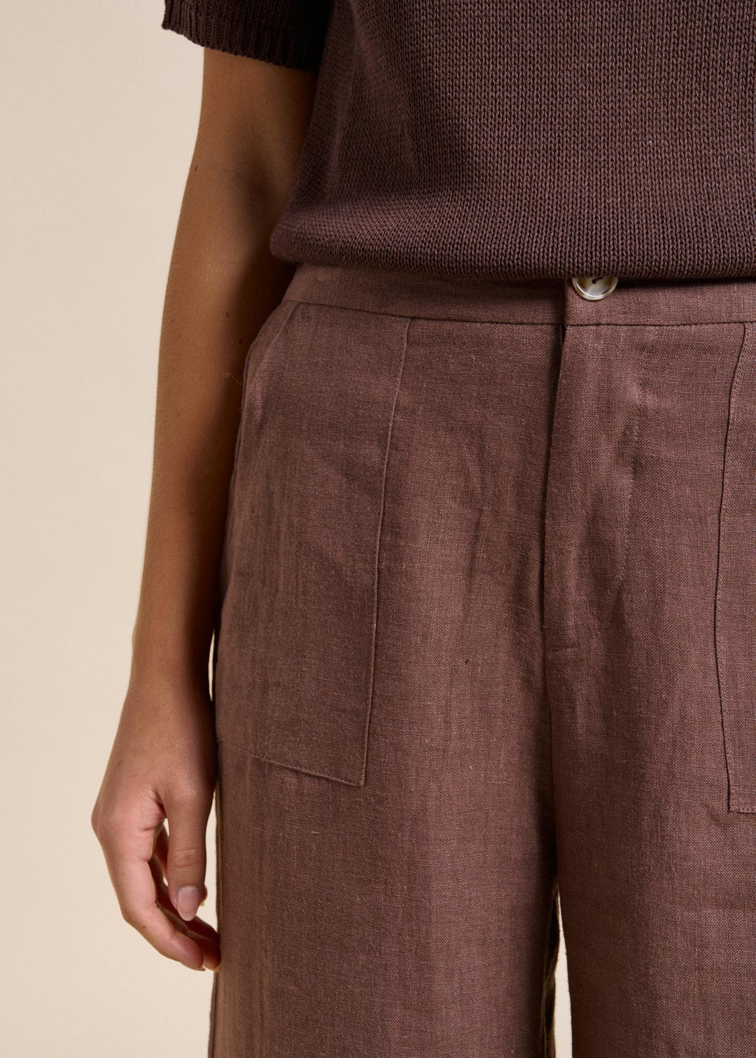 Brown pants worn by a person on a beige background