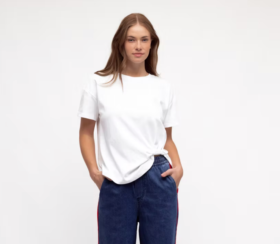 Woman wearing a white t-shirt and blue jeans on a plain background