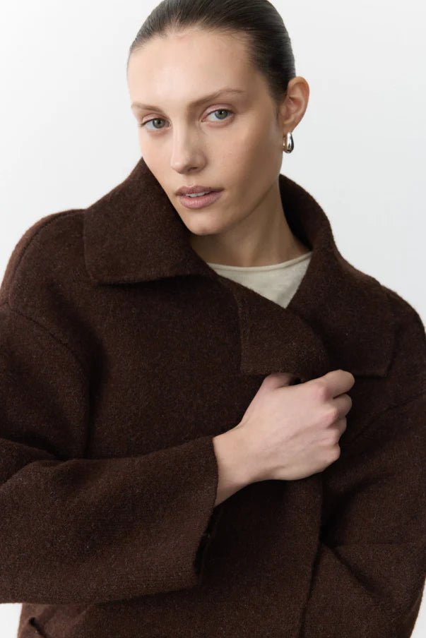 Woman wearing a brown coat against a white background
