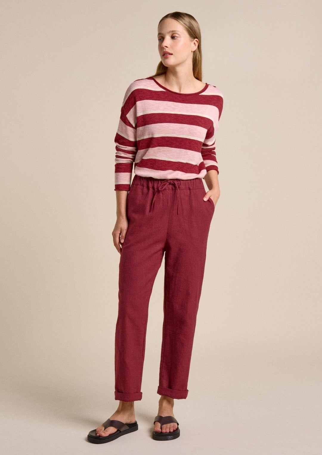 Woman wearing a red and white striped sweater with red pants on a beige background