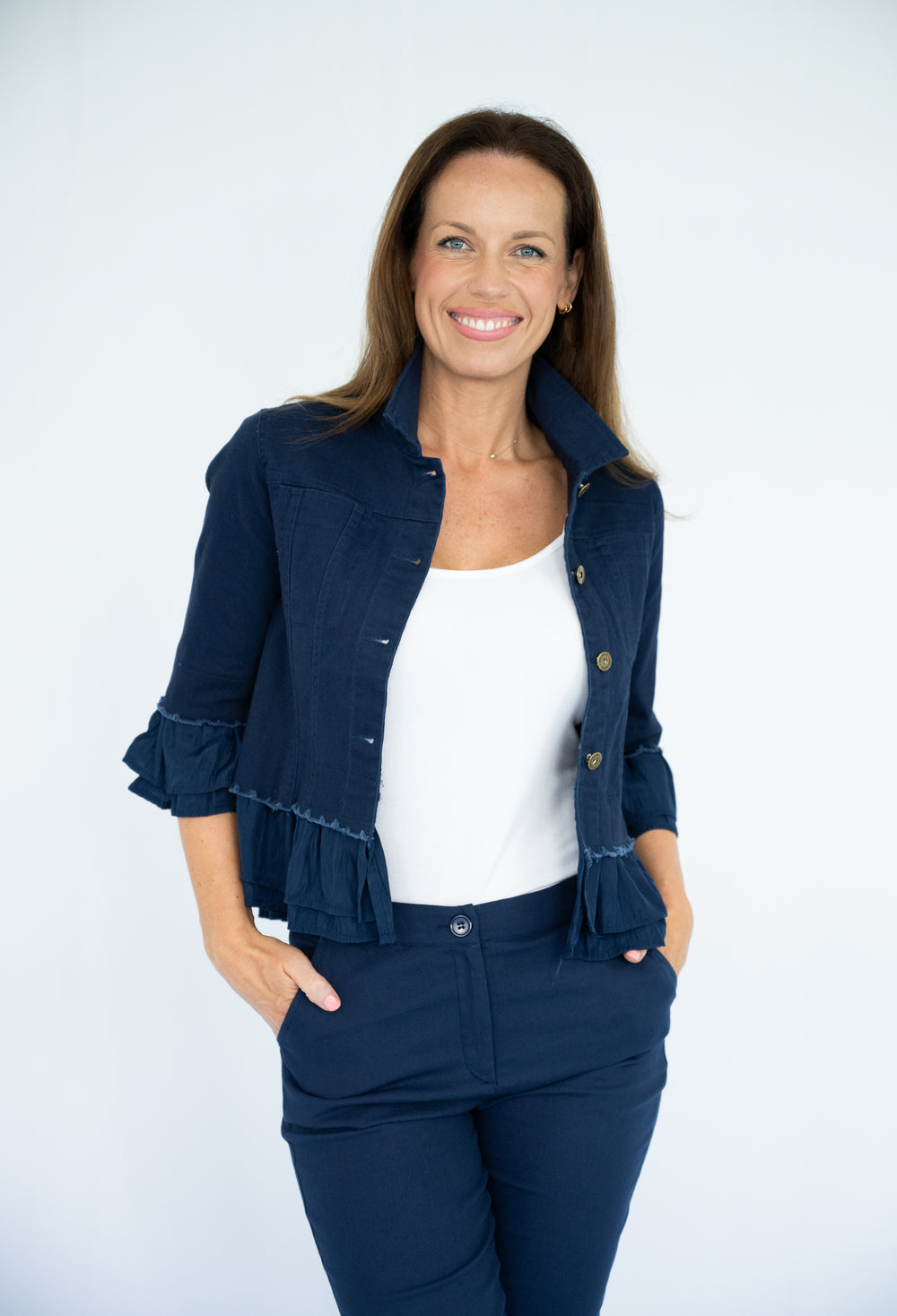 Woman wearing a navy blue jacket over a white shirt on a white background