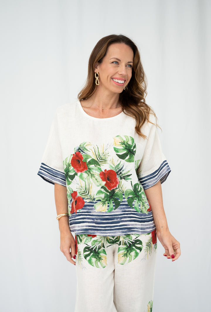Woman wearing a floral top and pants against a white background
