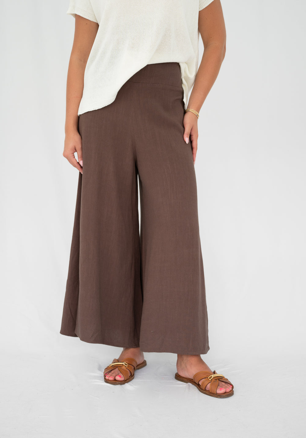 Person wearing brown wide-leg pants on a white background
