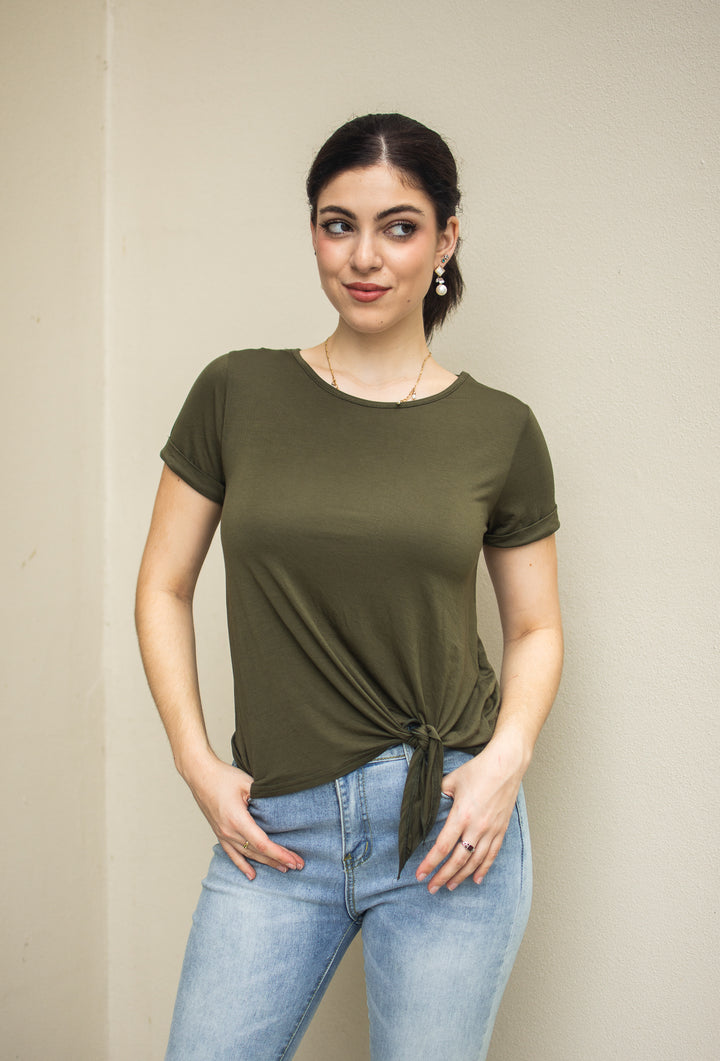 A woman wearing a green modal tee with cuffed sleeves and a tie front design, paired with blue jeans.
