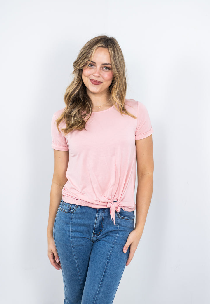 Woman wearing a pink modal t-shirt and blue jeans against a white background