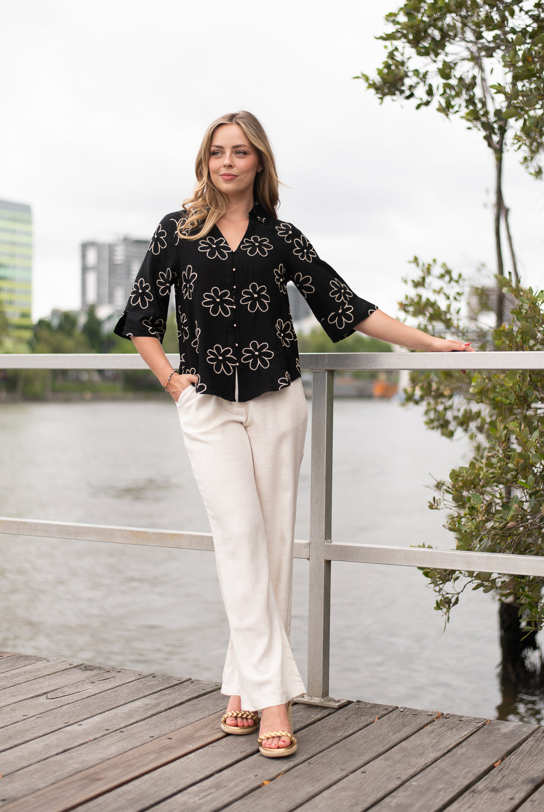 Woman standing on a wooden dock by a waterfront with a cityscape in the background