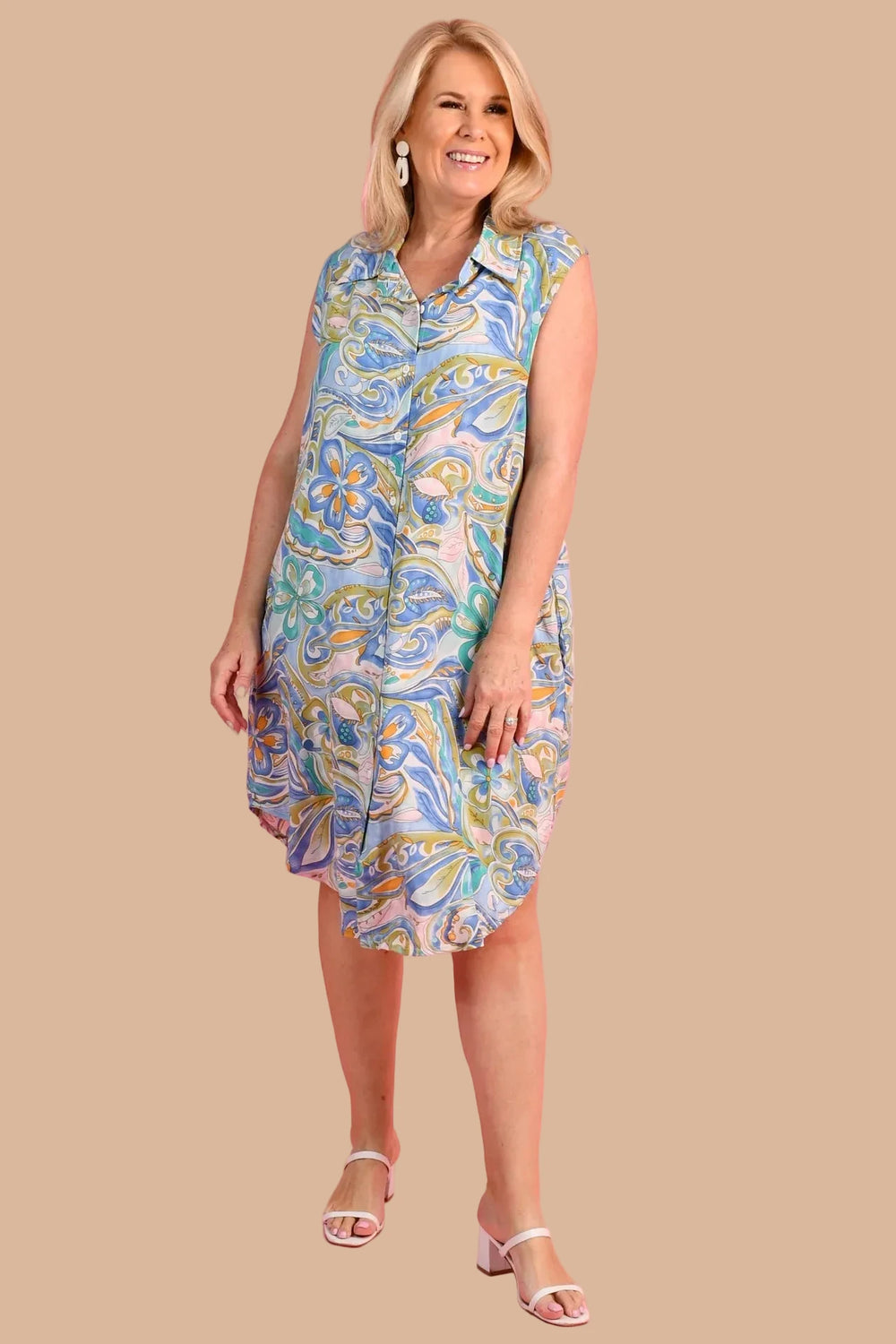 Woman wearing a colorful patterned dress on a pink background