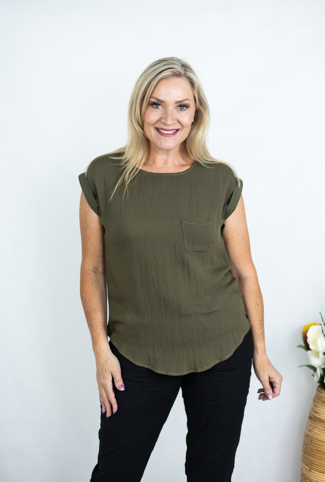 Woman wearing an olive green top with a pocket on a white background