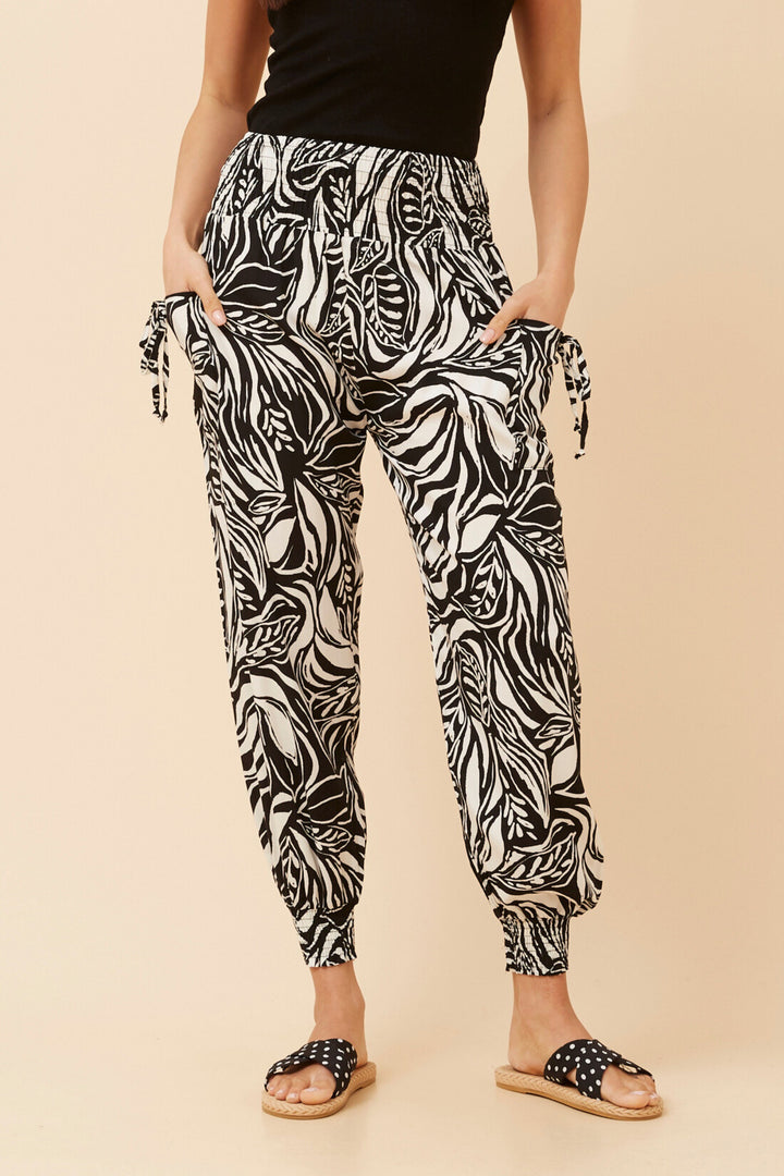 Person wearing black and white patterned pants on a beige background
