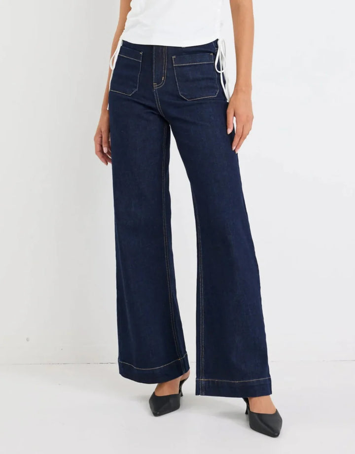 Dark blue wide-leg jeans worn by a person on a white background