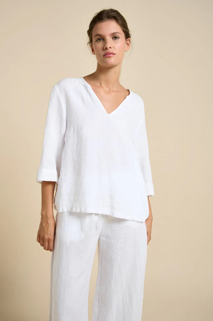 Woman wearing a white outfit against a beige background