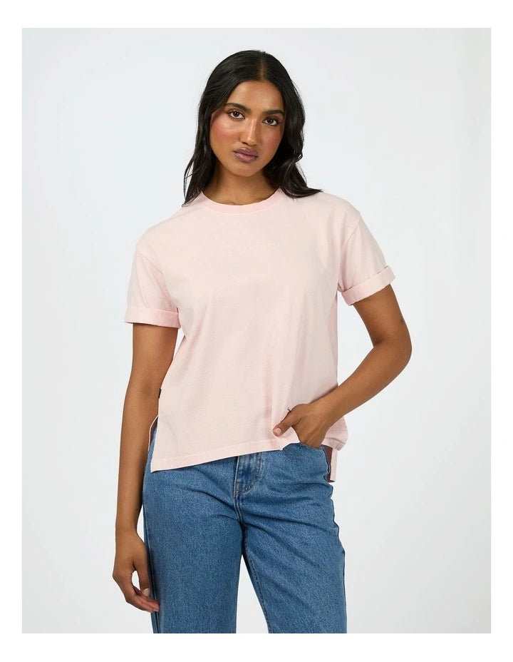 Woman wearing a light pink t-shirt and blue jeans on a white background