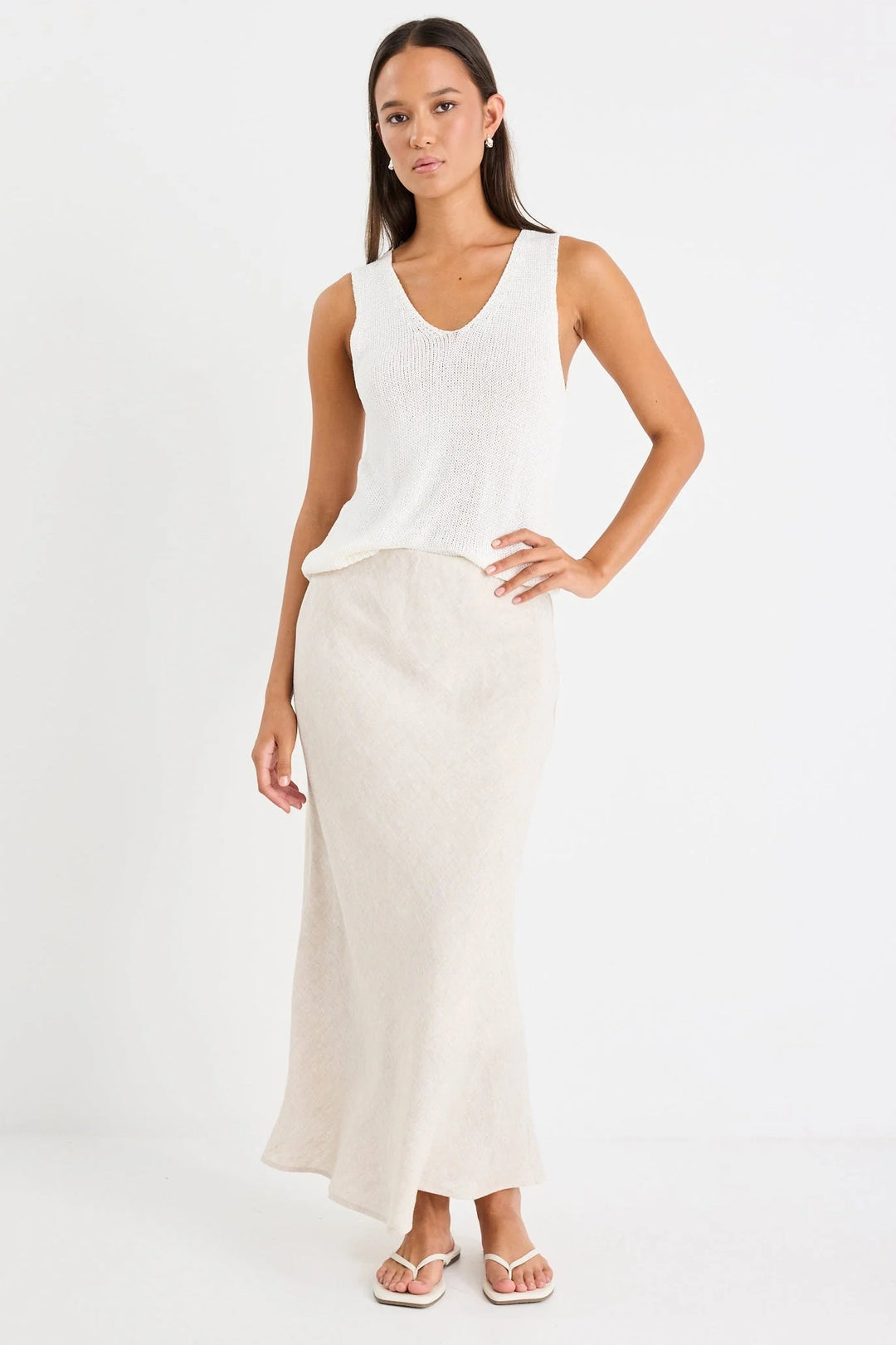 Woman wearing a white sleeveless top and long skirt on a white background