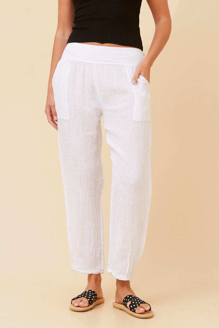 Person wearing white pants and black sandals on a beige background