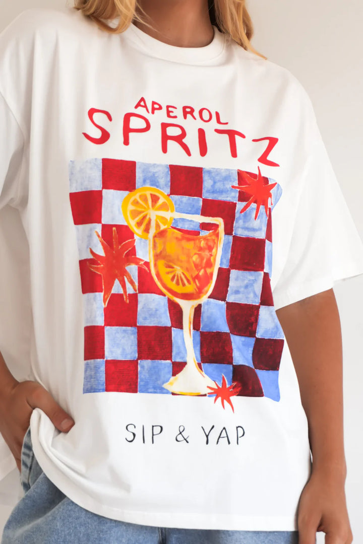 White t-shirt with Aperol Spritz graphic design featuring a cocktail and checkered pattern.