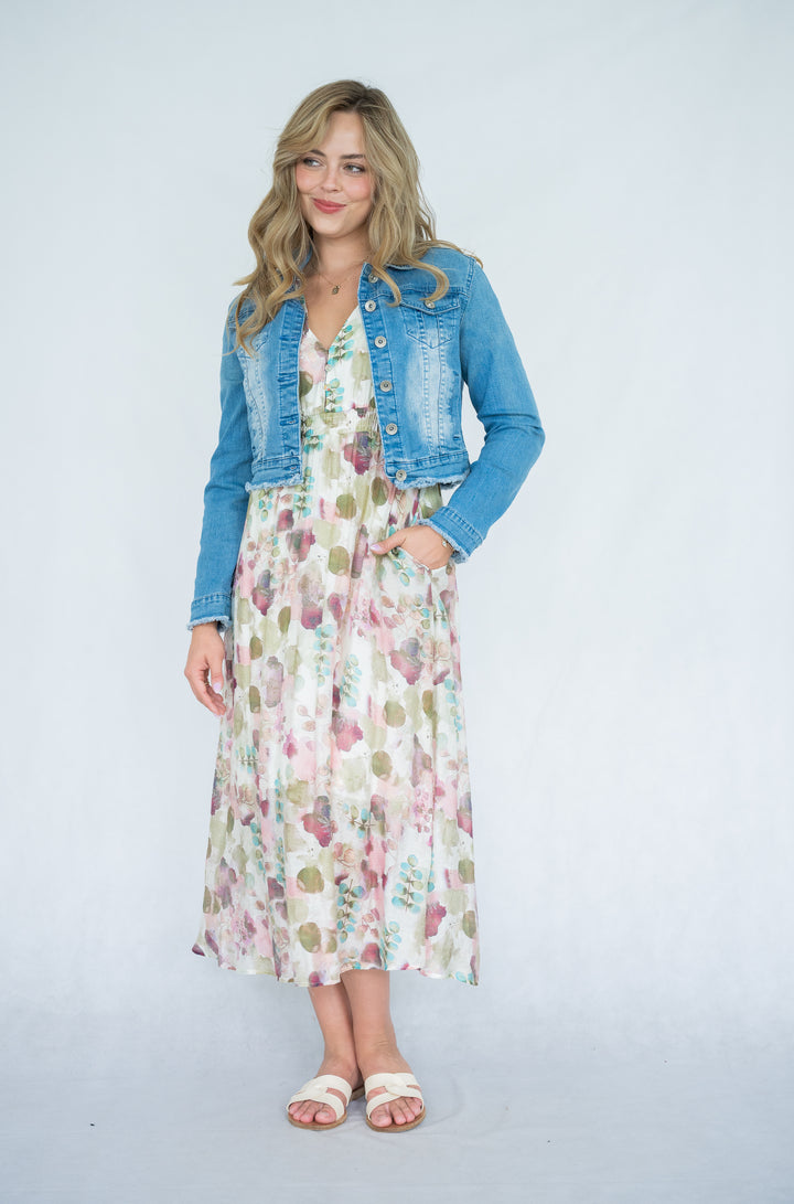 Woman wearing a floral dress with a blue denim jacket on a white background