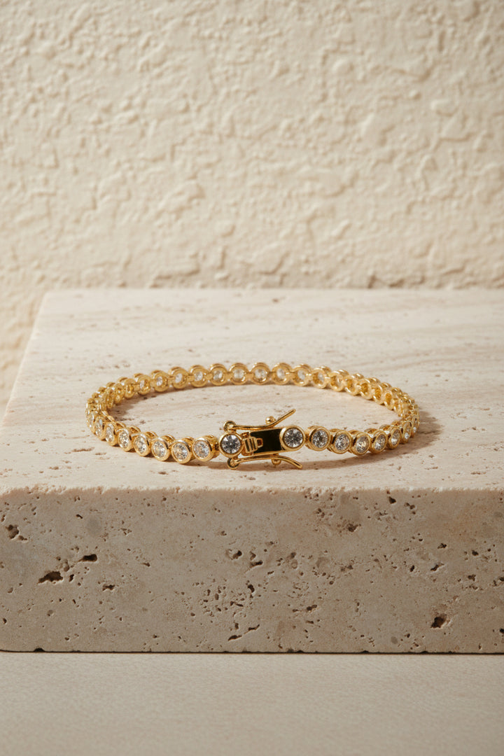Gold bracelet with clear stones on a white background