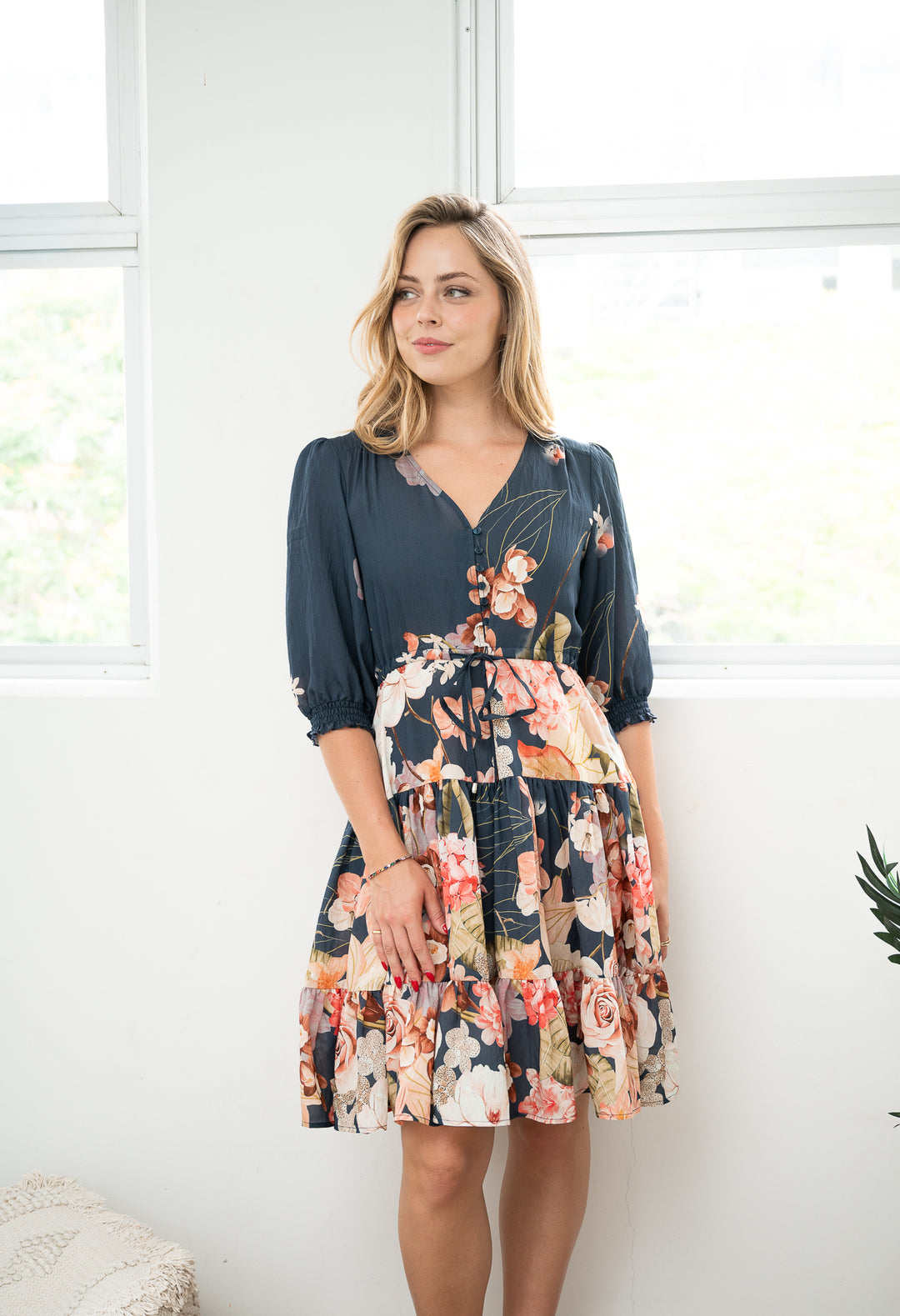 Woman wearing a two-tone dress with a floral pattern in a bright room.