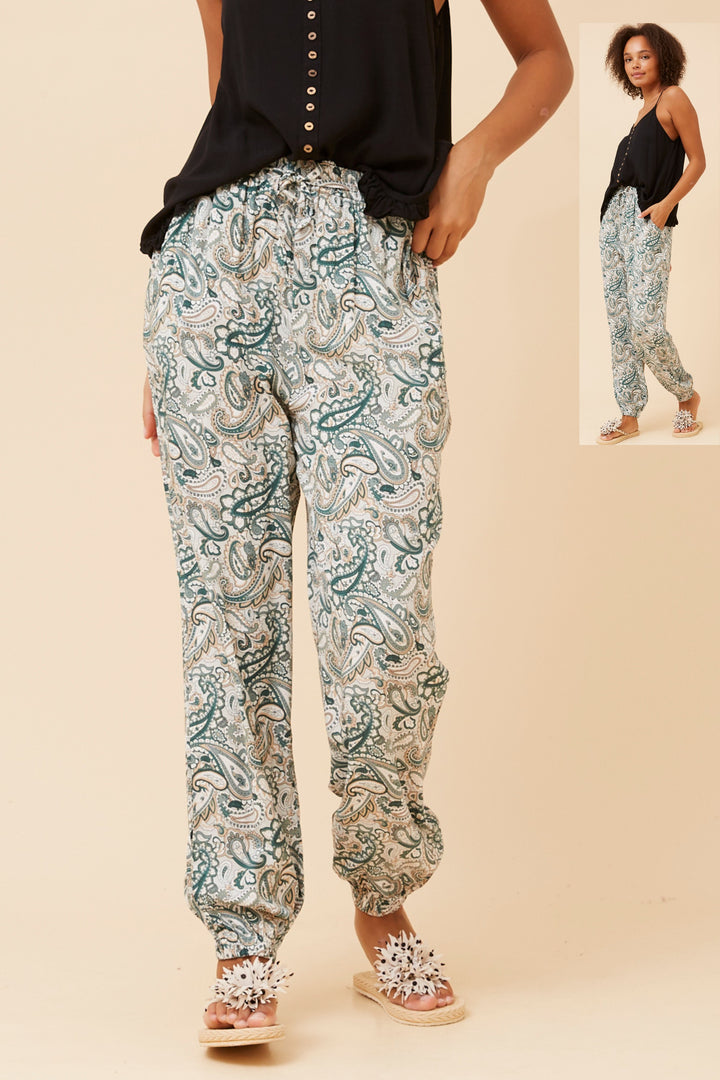 Person wearing paisley print pants on a beige background