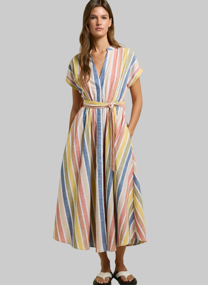 Woman wearing a colorful striped dress on a beige background