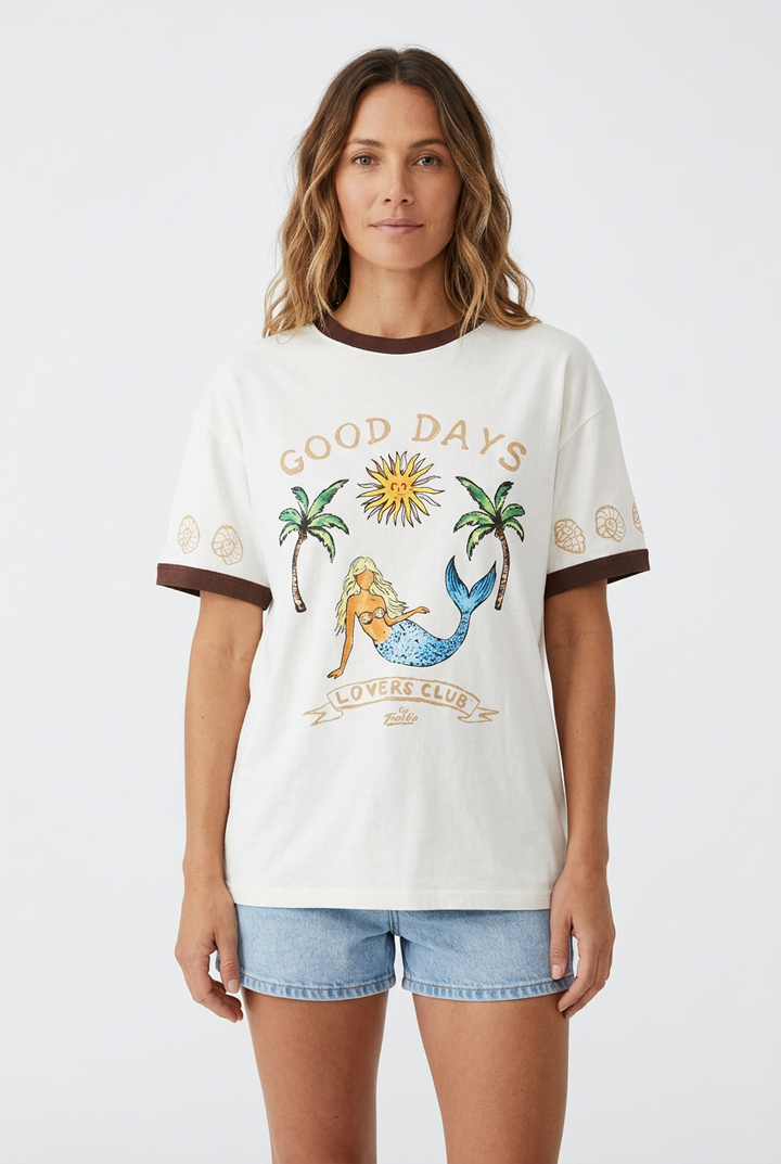 Three short-sleeve graphic T-shirts displayed on mannequin torsos in a store window. The shirts feature a mermaid and palm tree design with the text &