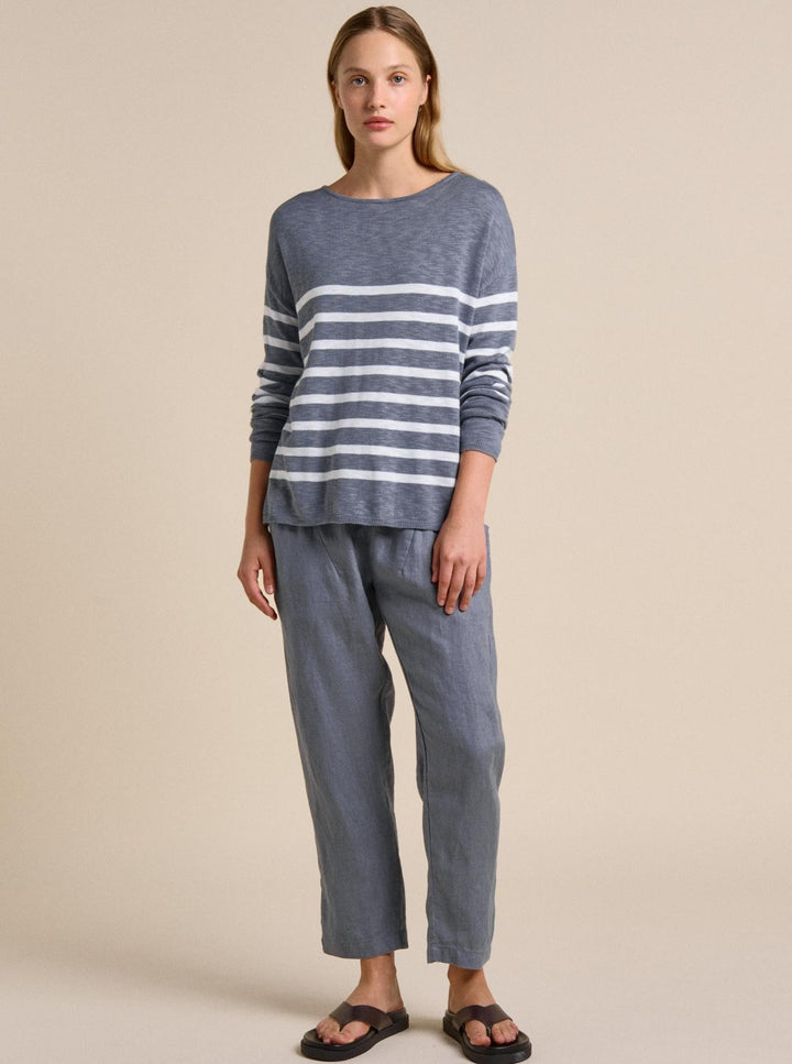 Woman wearing a blue and gray striped sweater and pants on a beige background