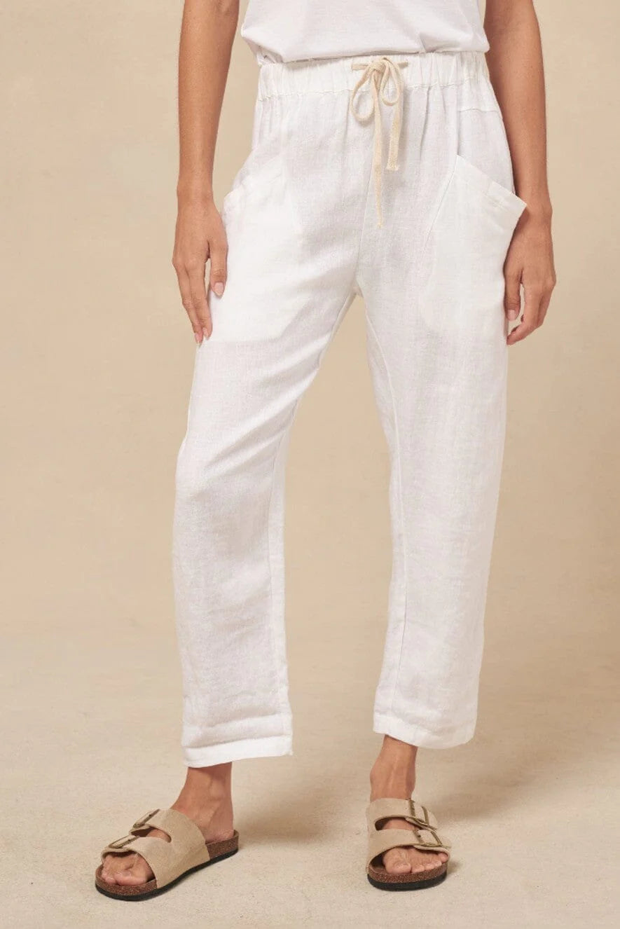 A pair of white linen pants with an elasticated waist and side-angled pockets, worn by a model standing against a neutral background.white linen pants women
linen pants australia
little lies linen pants
womens white linen trousers
elastic waist linen pants
coastal summer pants women
holiday linen pants