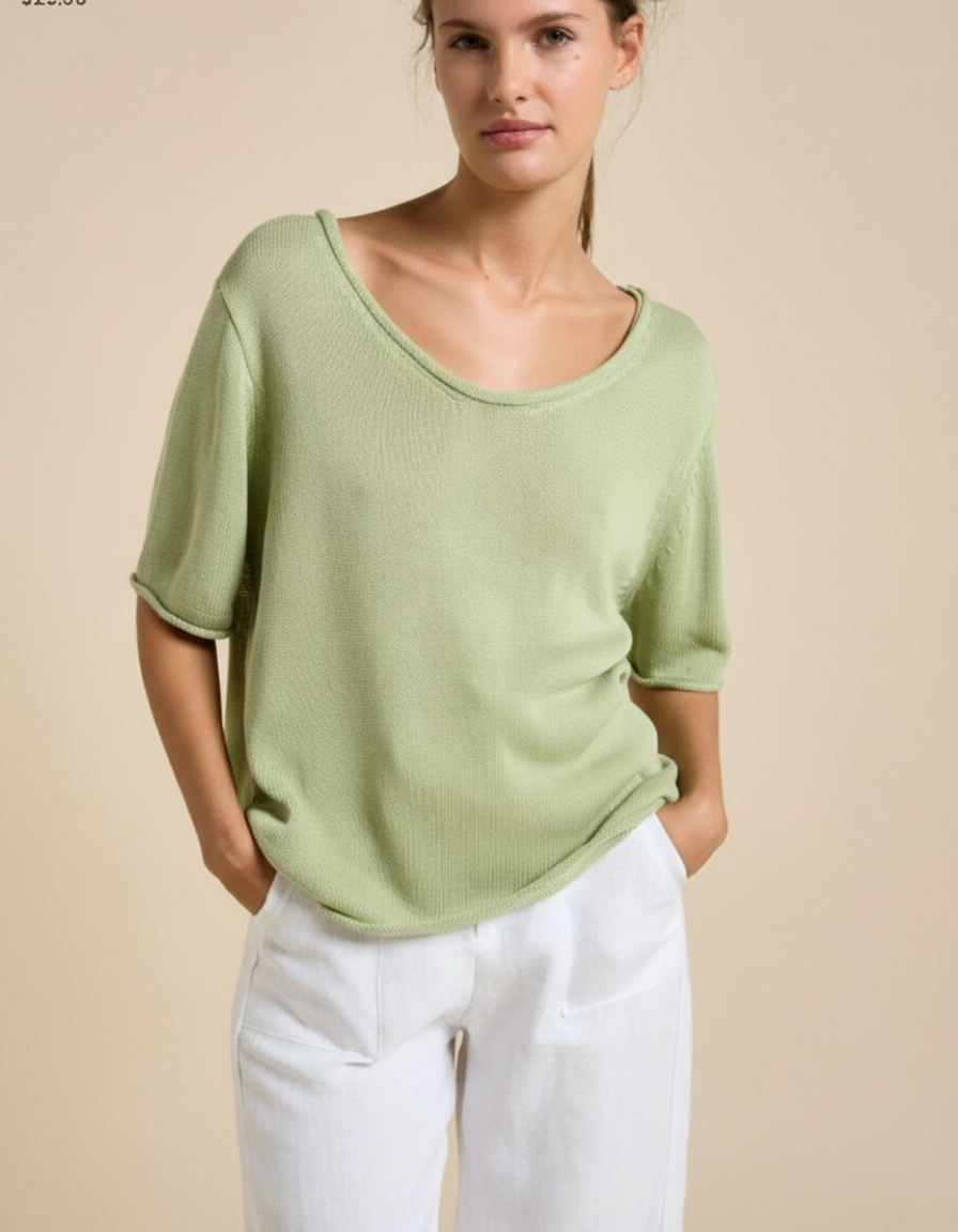 Woman wearing a light green top and white pants against a beige background